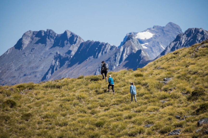 A group of people walking over a hill's crest.